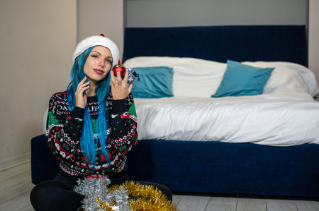 Portrait of beautiful caucasian hipster woman in Christmas clothes. Posing looking at camera holding colorful balls. Beauty, Christmas holidays, positivityの写真素材