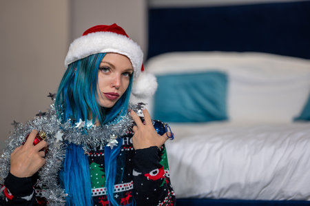 Portrait of a hipster Caucasian woman in Christmas clothes. She poses looking at the camera holding colorful balls and a silver decoration around her neck. Beauty, Christmas holidays, positivityの写真素材