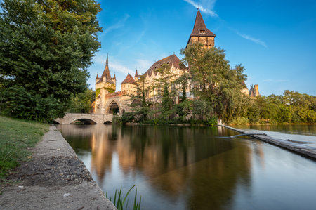 Budapest,Hungary.August 27,2022. Wide-angle lens shot, low angle towards Vajdahunyad Castle. Long exposure. Warm late afternoon light illuminates the facade. Fairytale atmosphere, travel destinations.の写真素材