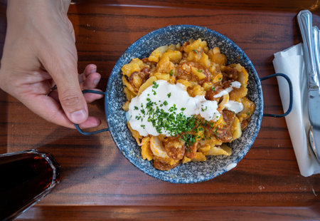 Top view of an appetizing dish with a local specialty: potatoes, meat, tomato, chopped parsley.