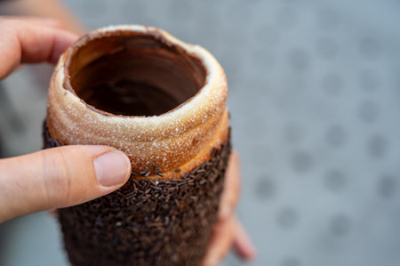 Budapest, Hungary, August 30, 2022. Close up of a Chimney cake topped with cream and chocolate pralines. Street food lifestyle.の写真素材