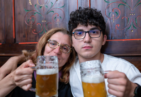 A middle-aged woman celebrates Mother's Day with her son by drinking a beer together. Looking into the camera, the lifestyle of celebrating with beer.の写真素材