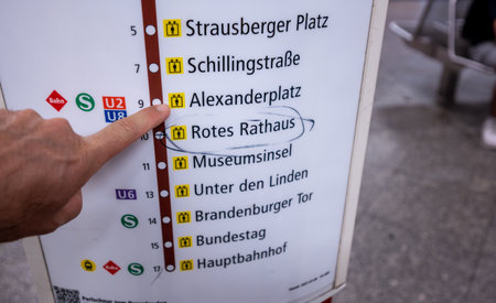 Berlin, Germany, August 10, 2023. On the subway, a hand points to the Alexanderplatz stop on the information board. Lifestyle using public transportation.の写真素材