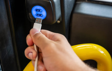 Berlin, germany, august 14, 2023. Hand plugging a data cable into a bus usb charger, powering...