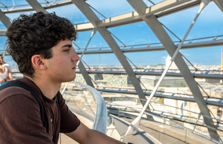 Berlin, germany, august 15, 2023. Young man adminding panoramic berlin skyline from the modern glass...