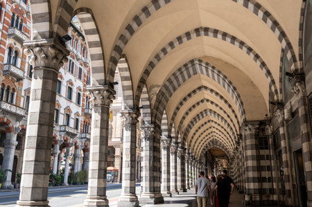 Genoa, liguria, italy. May 18, 2024. People walking along the grand architectural arcades of via xx settembre in genoa, italy, under a typical summer lightのeditorial素材