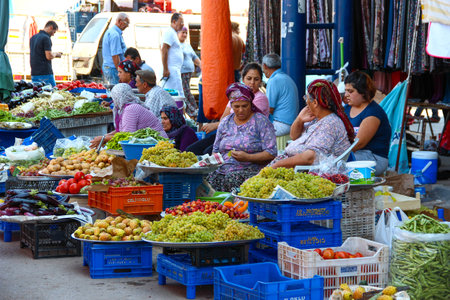 ANTALYA, TURKEY - Aug 14, 2012, View of a traditional street markets where old and young women selling fruit and vegetables and talking to the waiting customers, on Aug 14 2012 in ANTALYA, TURKEYのeditorial素材