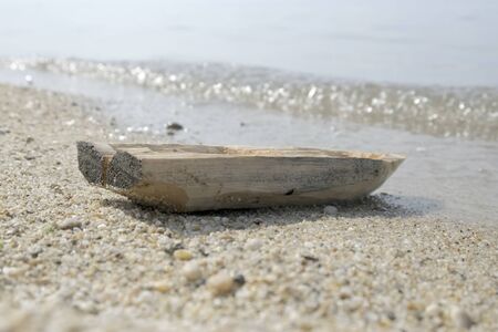 Abandoned lonely old toy wooden boat stands on the beach.の写真素材