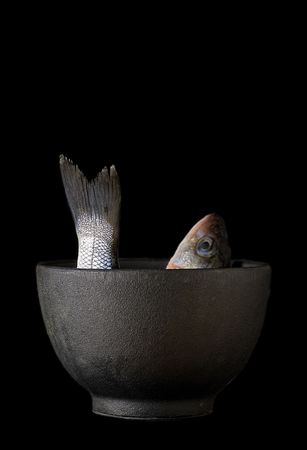 a sea bass in a rough textured iron bowlの写真素材
