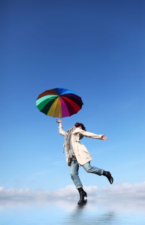 Girl jumping with umbrella over waterの写真素材