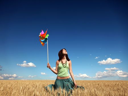 Girl with wind turbine at wheat field