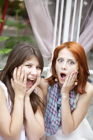 Two girls gossiping on bench at garden.の写真素材