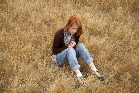 Lonely sad red-haired girl at fieldの写真素材