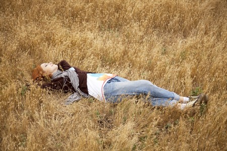 Young beautiful girl lying at yellow autumn field.の写真素材