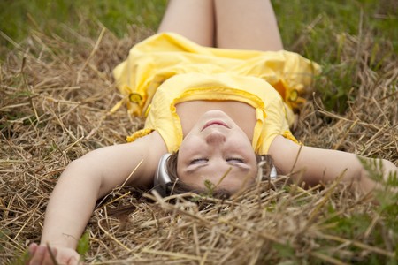 Young beautiful girl in yellow with headphones at field.の写真素材