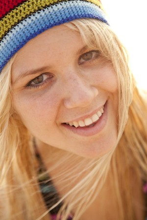 Beautiful young blonde girl in rastafarian hat. Sunlight is on background.の写真素材