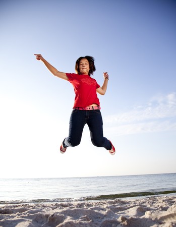 Beautiful brunet girl jumping on the beachの写真素材