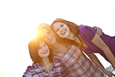 Portrait of three beautiful girls. With counter light on background.の写真素材