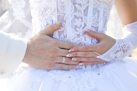 Groom and bride hand on bride's waist. Close-up view.