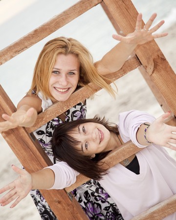 Portrait of two girls near wood stairs on the beach.の写真素材