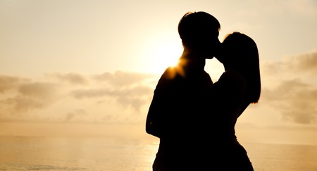 Couple kissing in sunrise at the beach.の写真素材