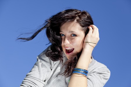 Portrait of beautiful brunette girl on blue sky background.