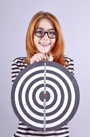 Red-haired girl with dartboard. Studio shot.の写真素材