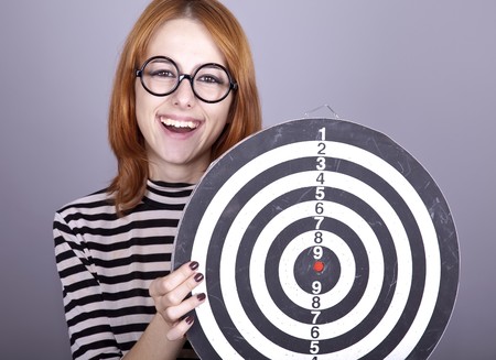 Red-haired girl with dartboard. Studio shot.の写真素材