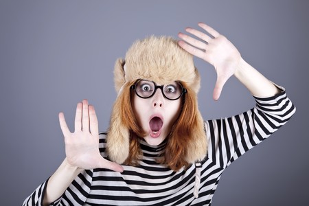 Surprise  girl in winter cap and glasses. Studio shot.