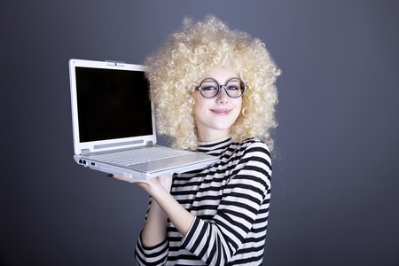 Portrait of funny girl in blonde wig with laptop. Studio shot.の写真素材