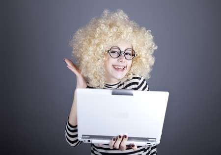 Portrait of funny girl in blonde wig with laptop. Studio shot.の写真素材