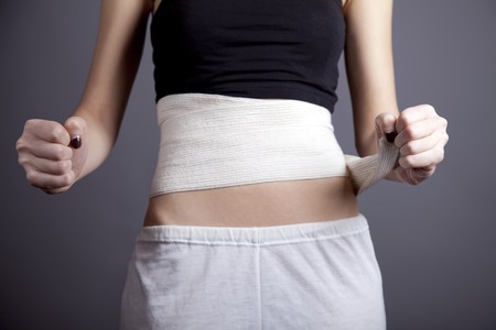 Strong girl's body with with elastic bandage on abs. Studio shot.の写真素材