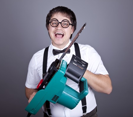 Portrait of mad fashion men in suspender with bow tie and glasses keeping portable saw. Studio shot.の写真素材