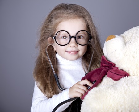 Little girl with  stethoscope and bear cub. Studio shot.の写真素材