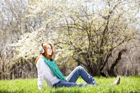 Redhead girl with headphone in the park.の写真素材
