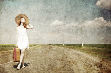Lonely girl with suitcase at country road.Photo in old image style.の写真素材