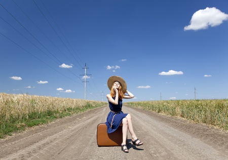 Lonely girl with suitcase at country road. の写真素材