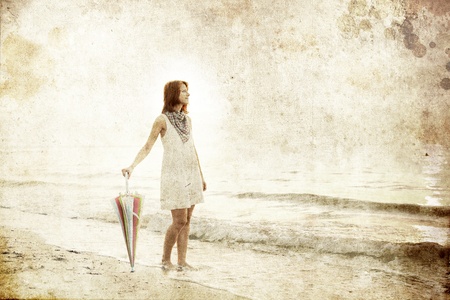 Girl with umbrella at sea coast. Photo in old image style.の写真素材