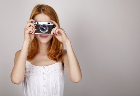 Redhead girl in white dress with vintage camera. Studio shot.の写真素材