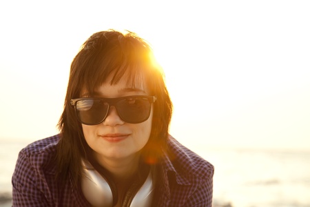 Beautiful brunette girl with headphones at beach sand in sunrise time.の写真素材