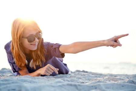 Beautiful redhead girl with headphones at beach sand in sunrise time.の写真素材