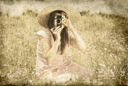Retro style girl at countryside with camera.