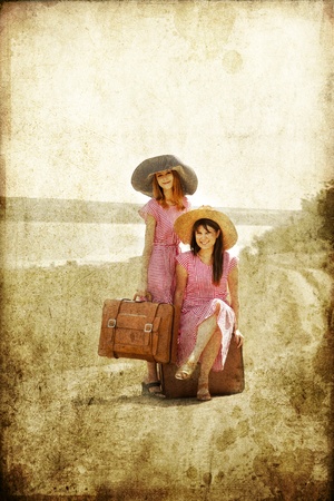 Two retro style girls with suitcases at countryside.の写真素材