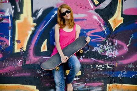 Style girl with skateboard near graffiti wall.の写真素材
