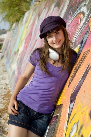 Beautiful brunette girl with headphones and graffiti wall at background.の写真素材