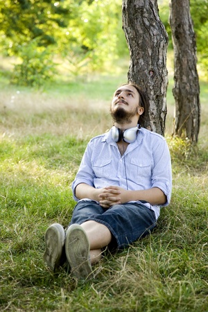 Man sitting on green grass with headphones.の写真素材