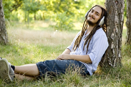 Man sitting on green grass with headphones.の写真素材