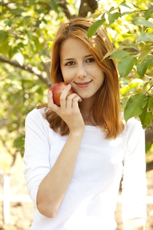 Beautiful young redhead woman standing near the apple tree.の写真素材