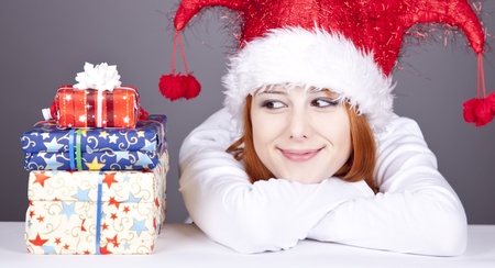 Funny red-haired girl in christmas cap with gift boxes.の写真素材