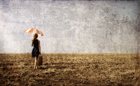 Redhead girl with umbrella at windy field.の写真素材